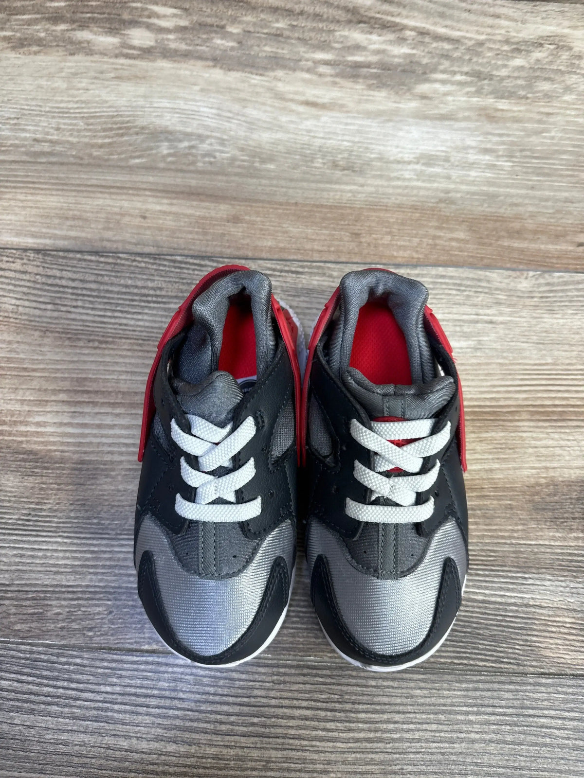 Top view of toddler Nike Huarache shoes size 8C in dark smoke grey and red with white laces on wood floor
