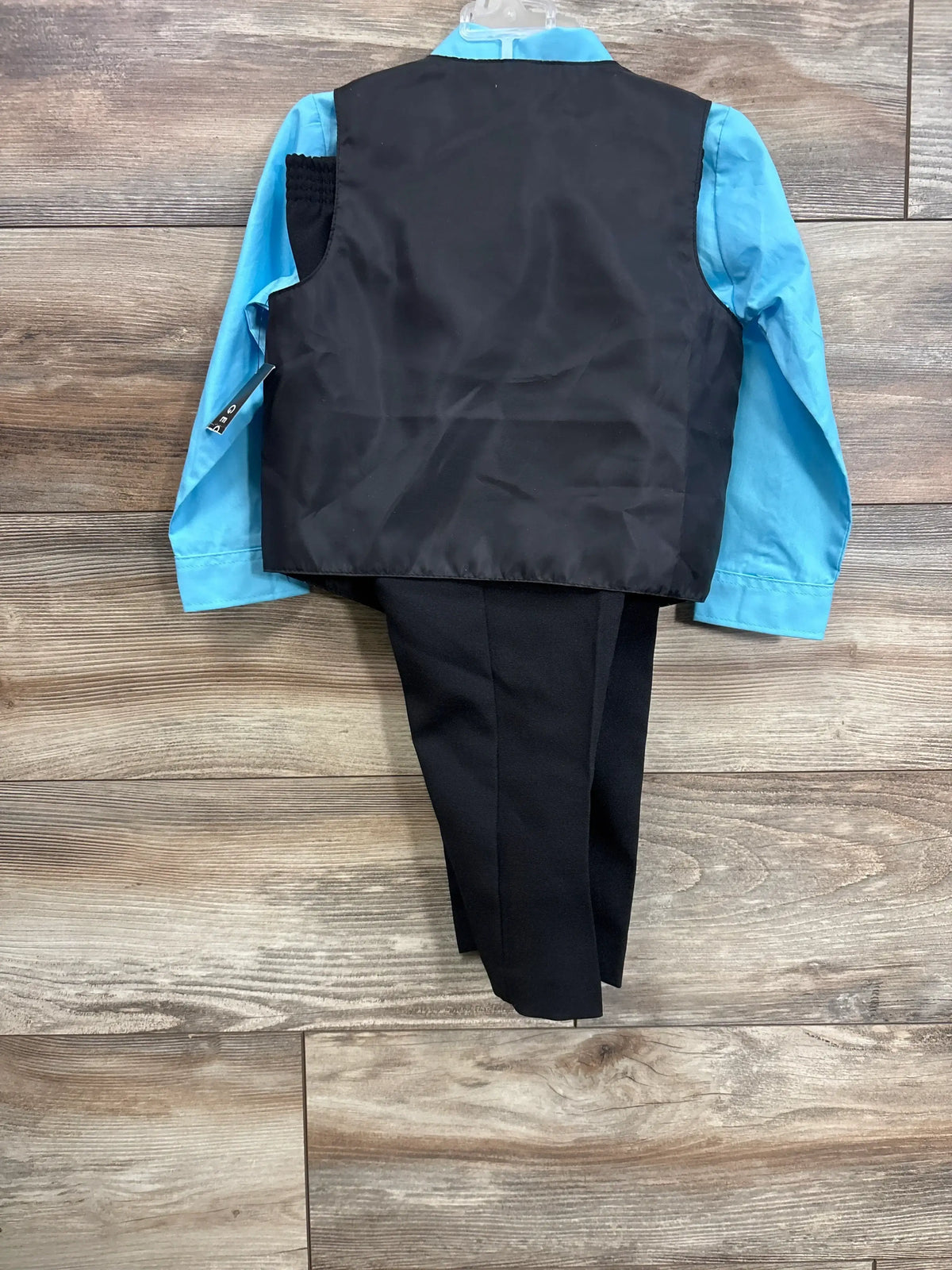Back view of boys 4-piece suit (3T) showing black vest over blue shirt and black pants on wood background
