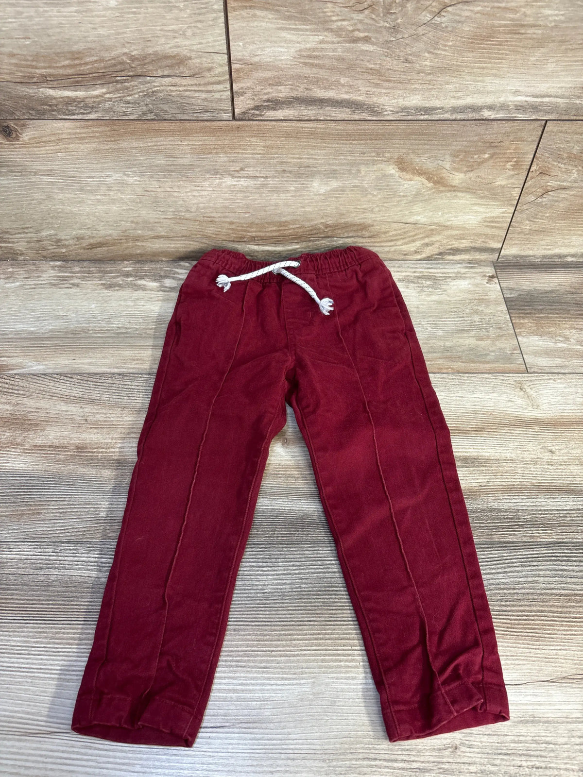 Front view of Cat and Jack red drawstring joggers in size 3T showcasing tapered legs, pockets, and adjustable waist on a wood look floor