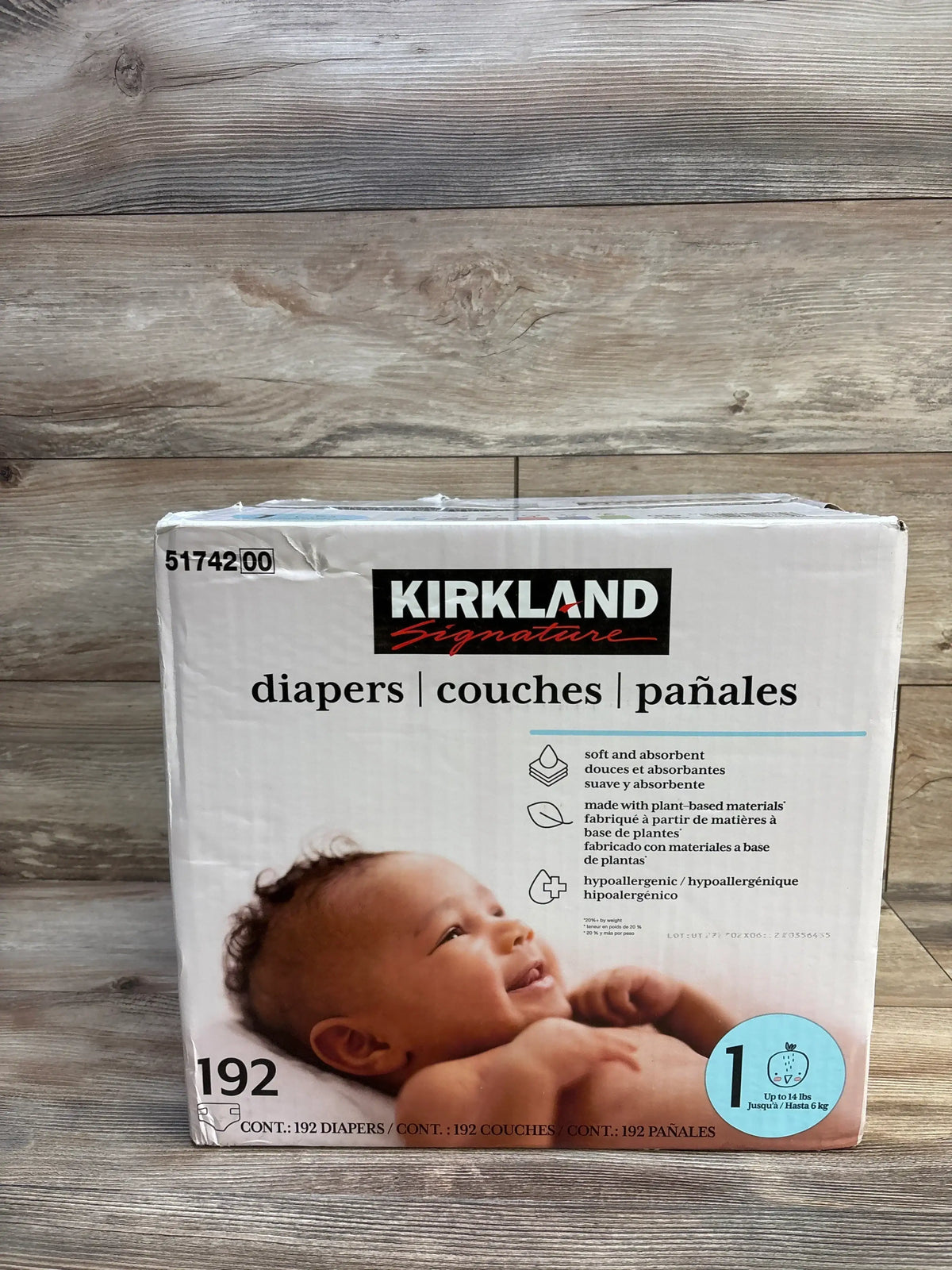 Front view of Kirkland Signature size 1 diaper box 192-pack showing branding, baby photo, and size badge on wooden background