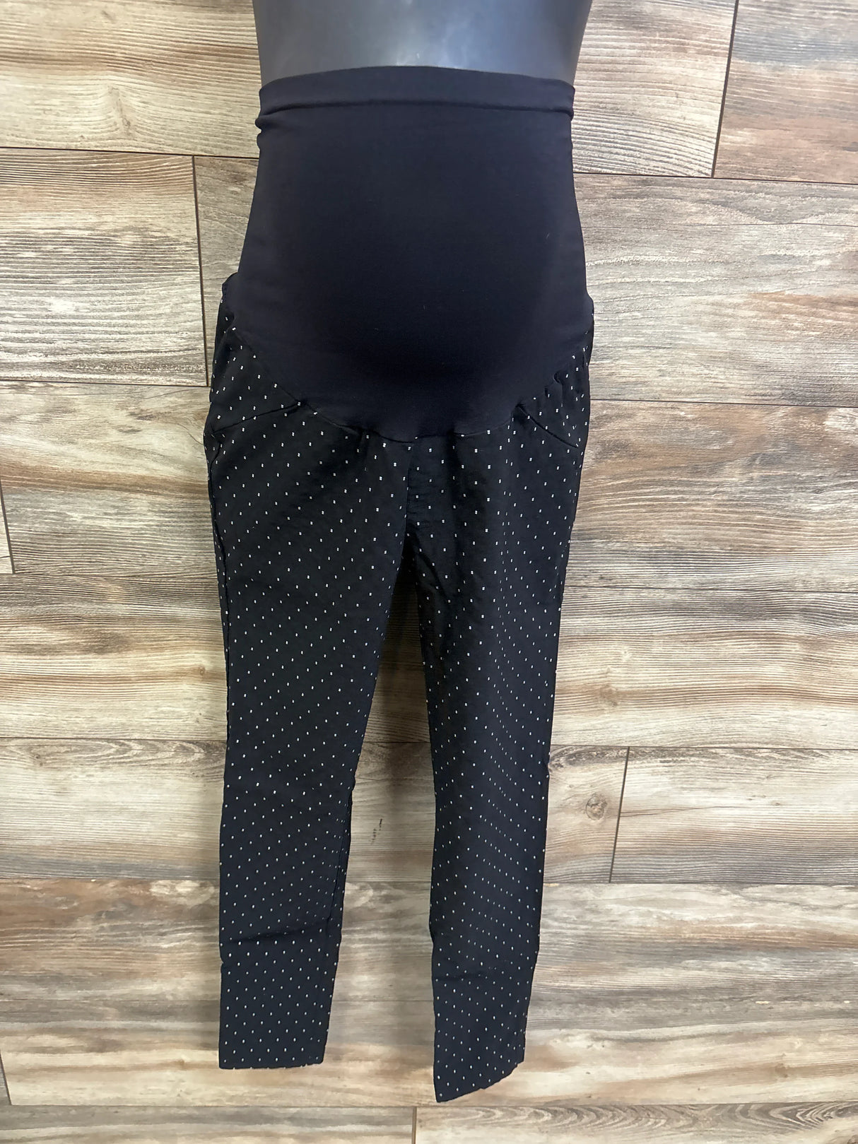 Front view of Motherhood Maternity full panel black pants with over-belly panel, tapered legs, white dot print on wood