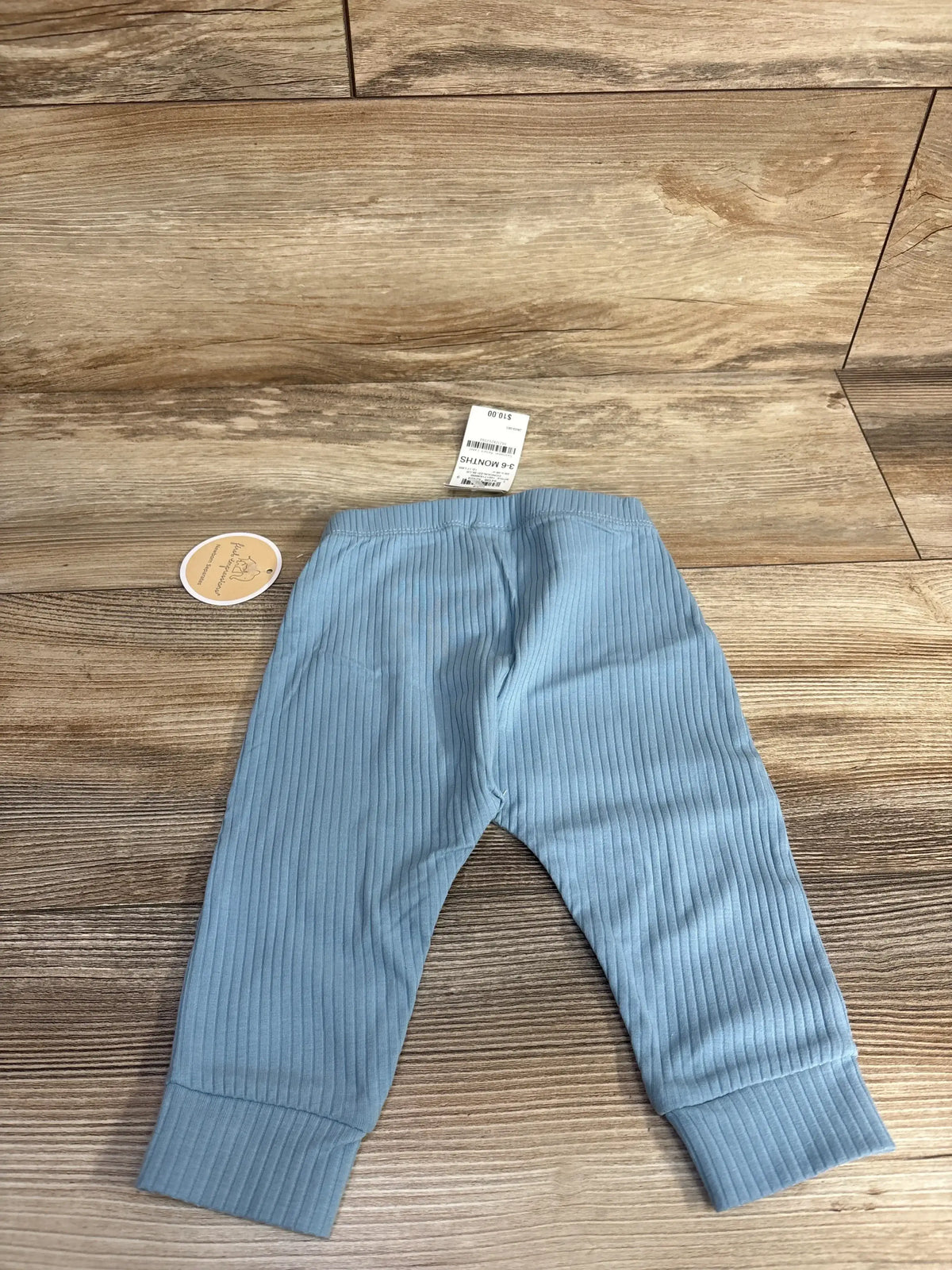 Light blue ribbed baby pants size 3-6 months on wood background, resale kids clothing