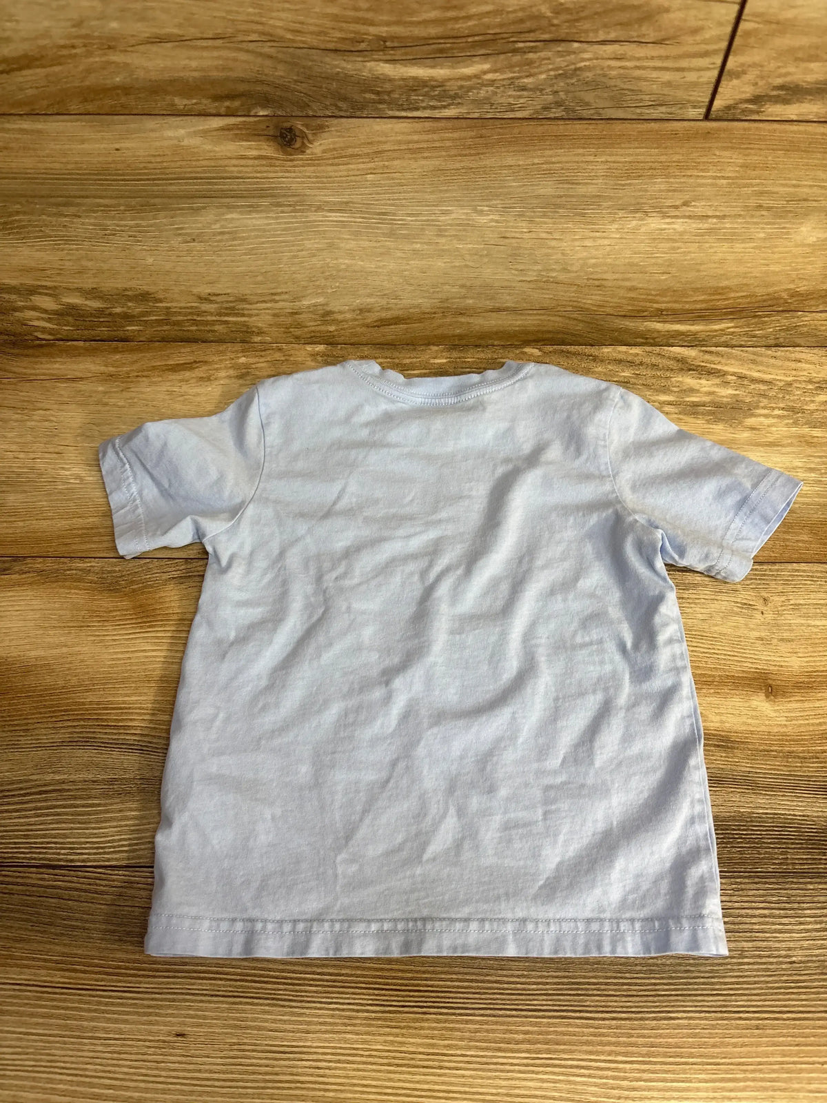 Back view of Adidas toddler soccer T-shirt size 4T showing plain light blue back, short sleeves and crew neck on wooden floor