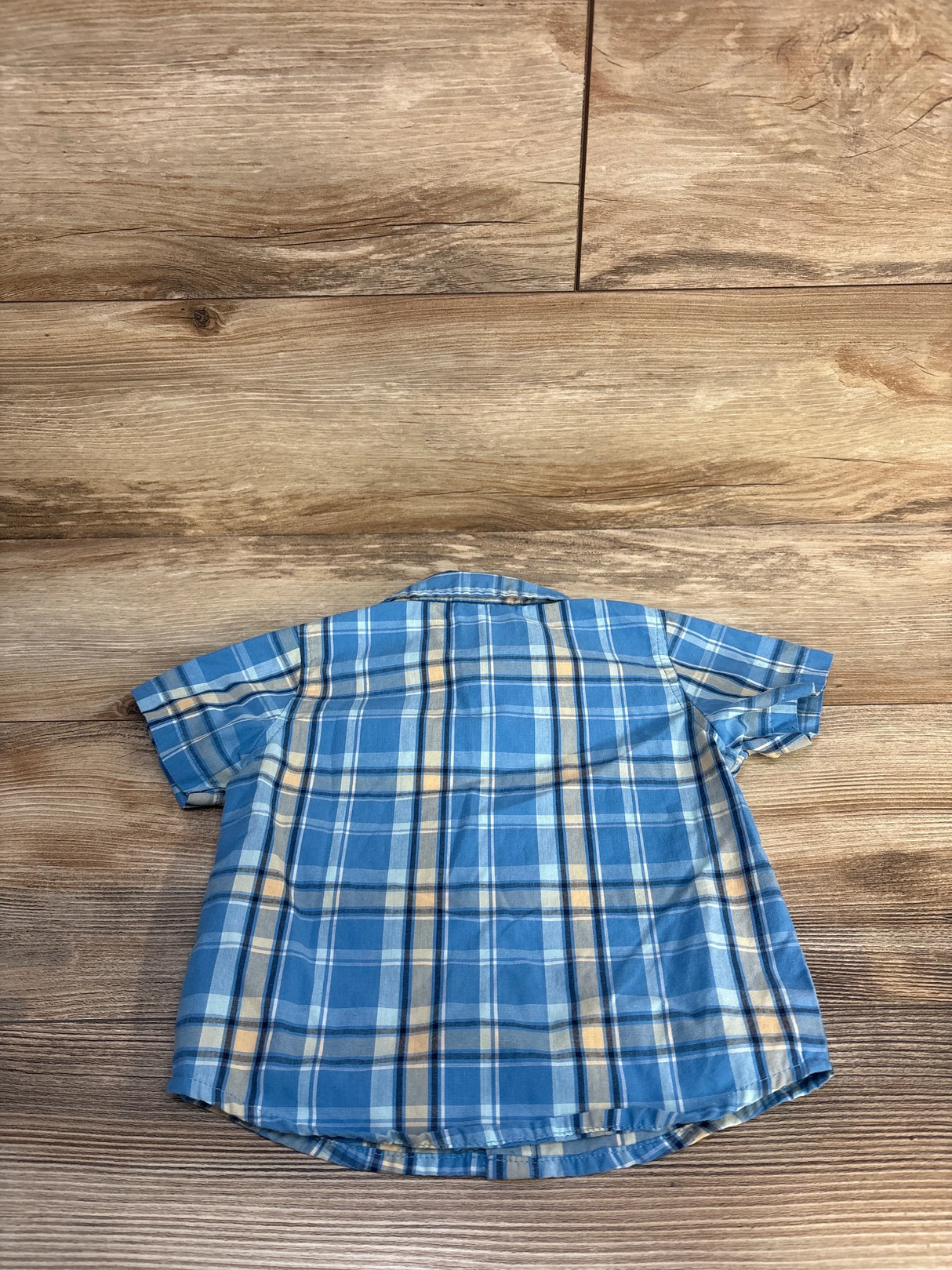 Back of Wrangler toddler plaid button-up shirt, 18 months, short sleeves, blue and yellow, on wood background