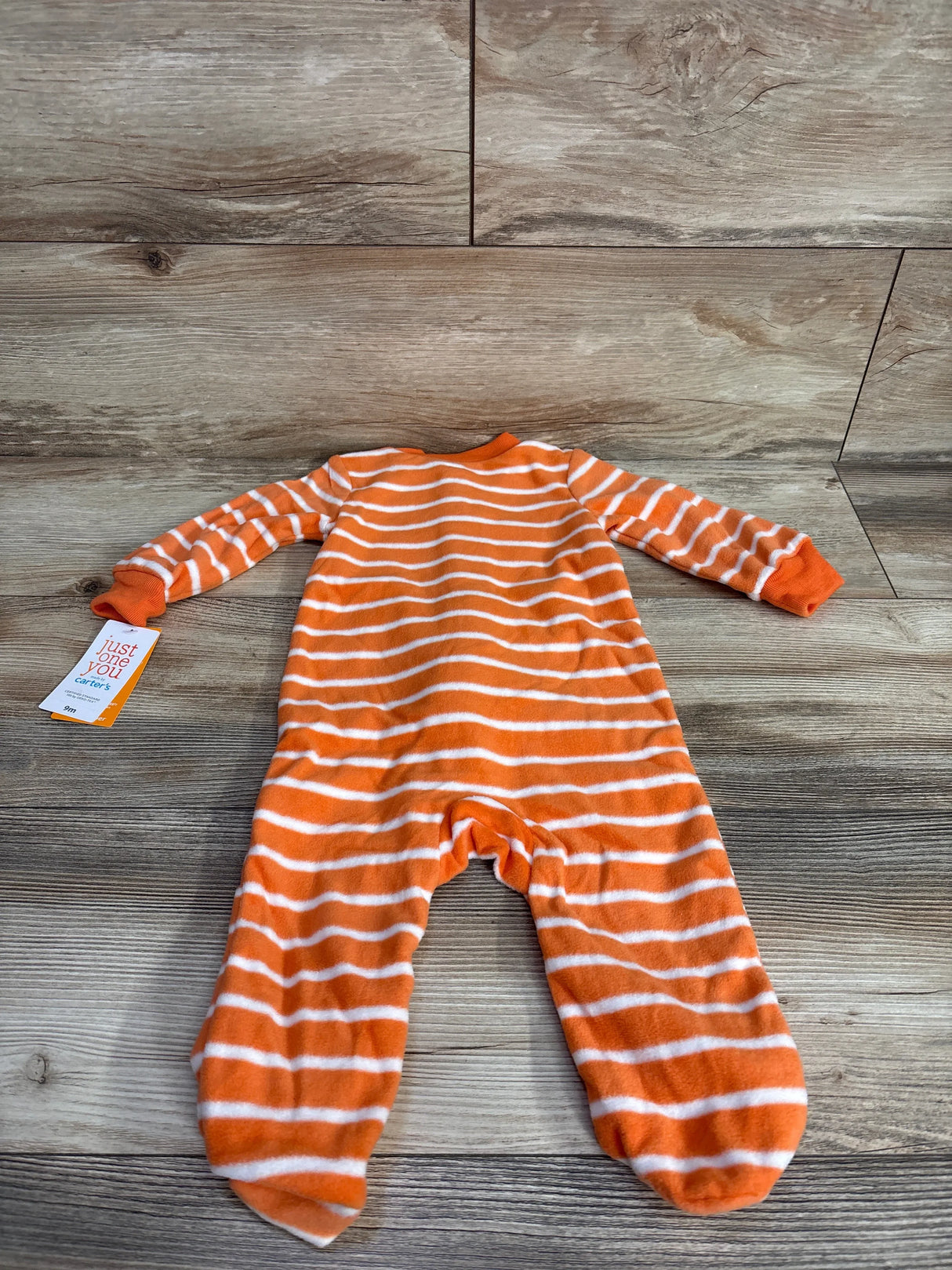 Orange and white striped baby onesie on wooden floor, Carter's brand tag visible