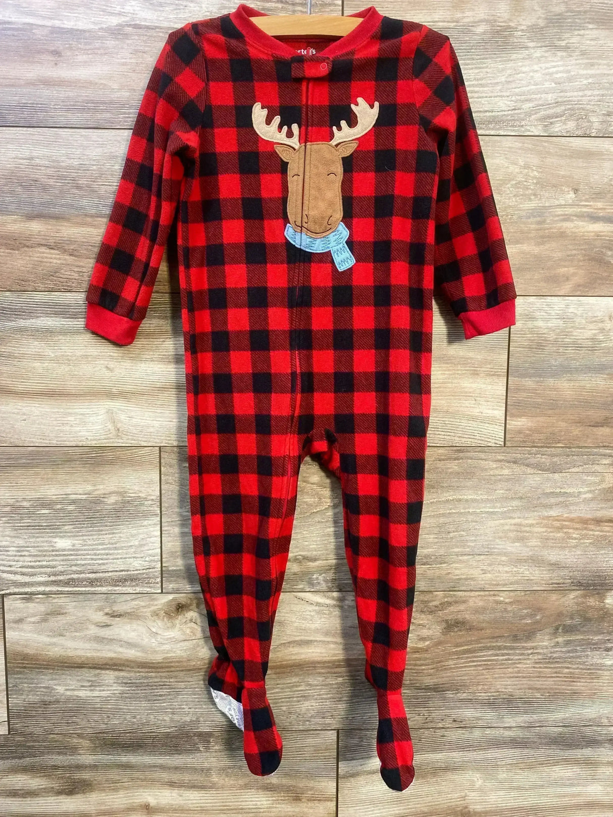 Flat lay of Just One You red and black buffalo check footed blanket sleeper sz 3T showcasing moose applique and front zipper on wood plank floor