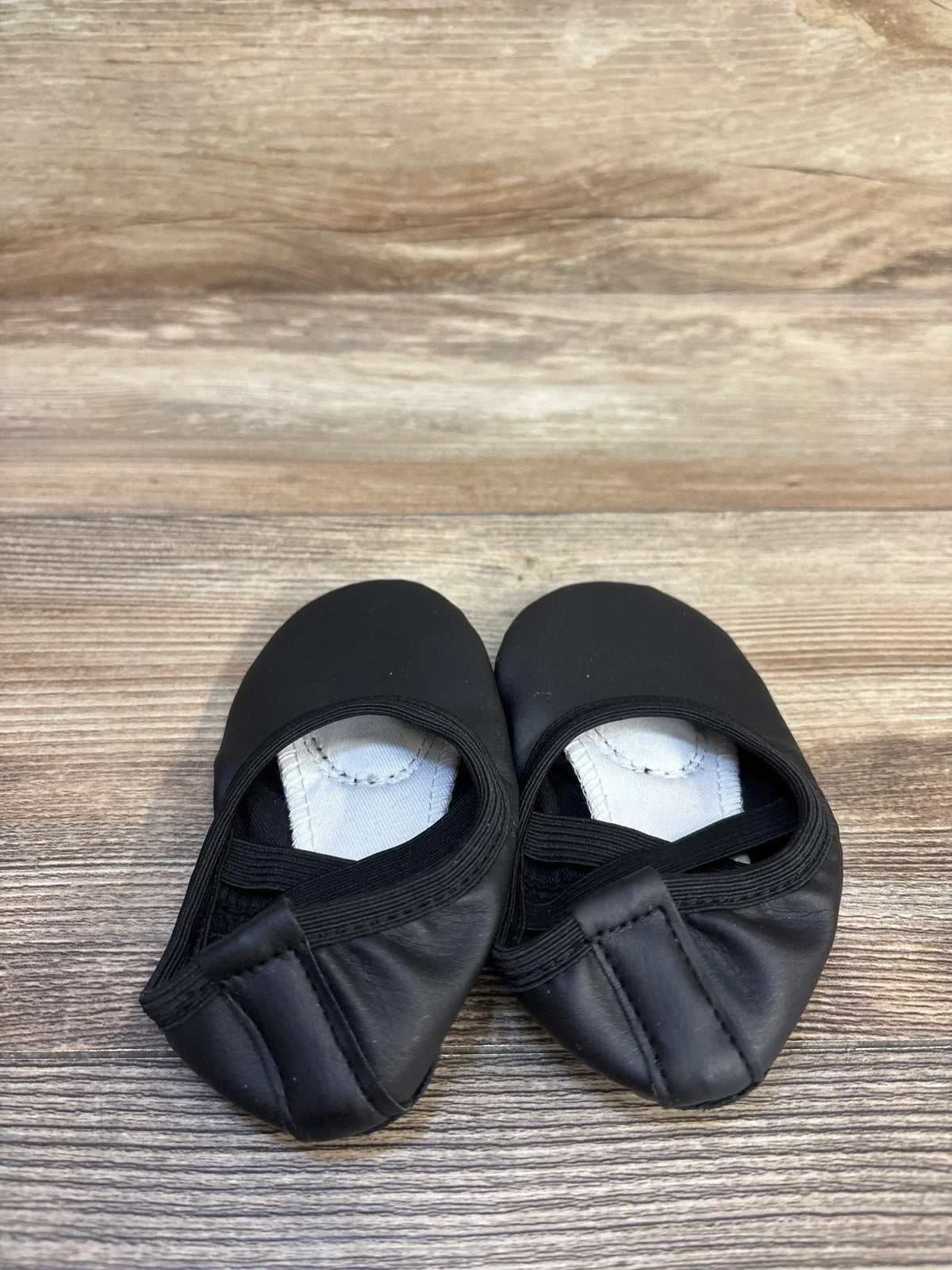 Pair of black toddler ballet shoes with elastic straps on wood background