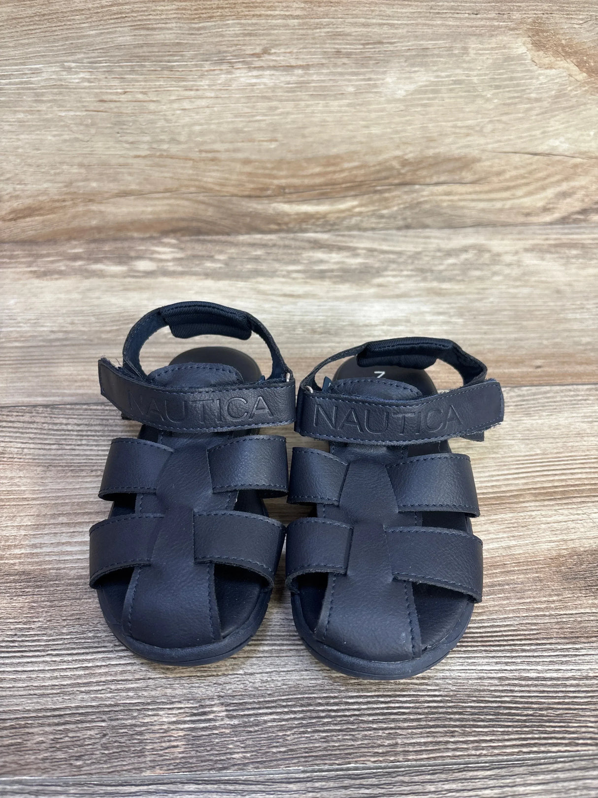 Front view of Nautica toddler fisherman sandals (size 9C) showcasing woven closed-toe straps and ankle hook-and-loop closure on wood background