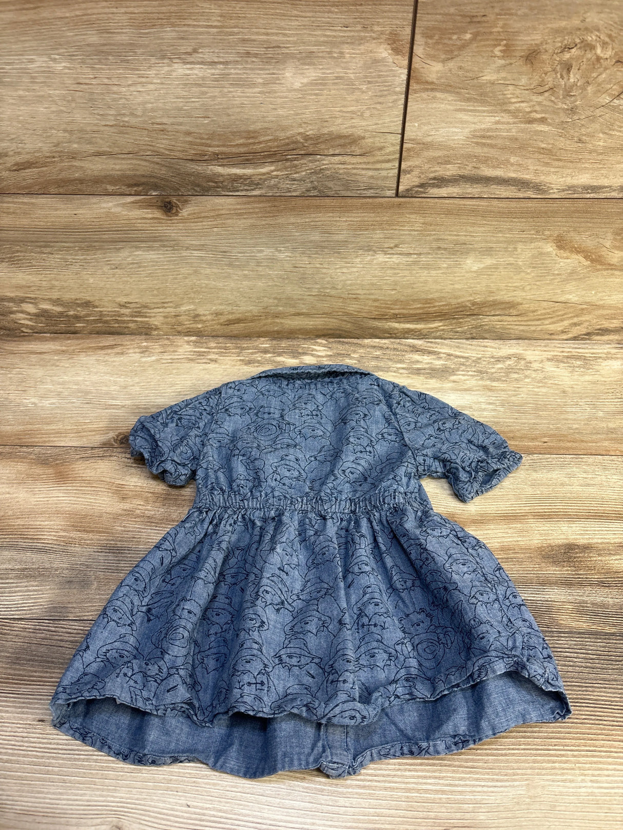 Back flat-lay of Baby Gap Paddington chambray dress 12-18M showing printed bear faces, elastic waist, puff sleeves on wood