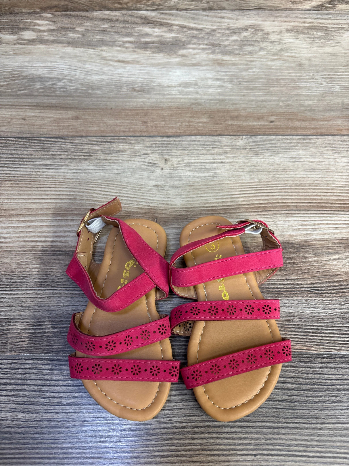 Top-down view of Ositos pink slingback sandals size 5C showcasing three floral-cut straps and buckle slingback on wood plank background