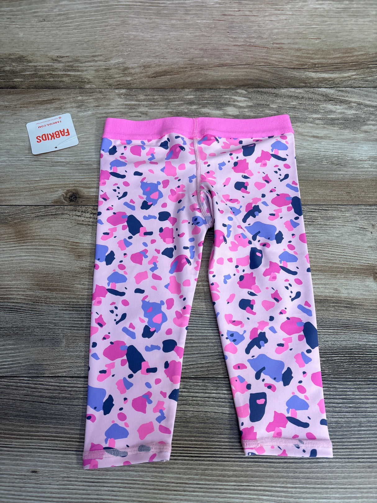 Pink and purple girls' leggings with abstract print on wood background