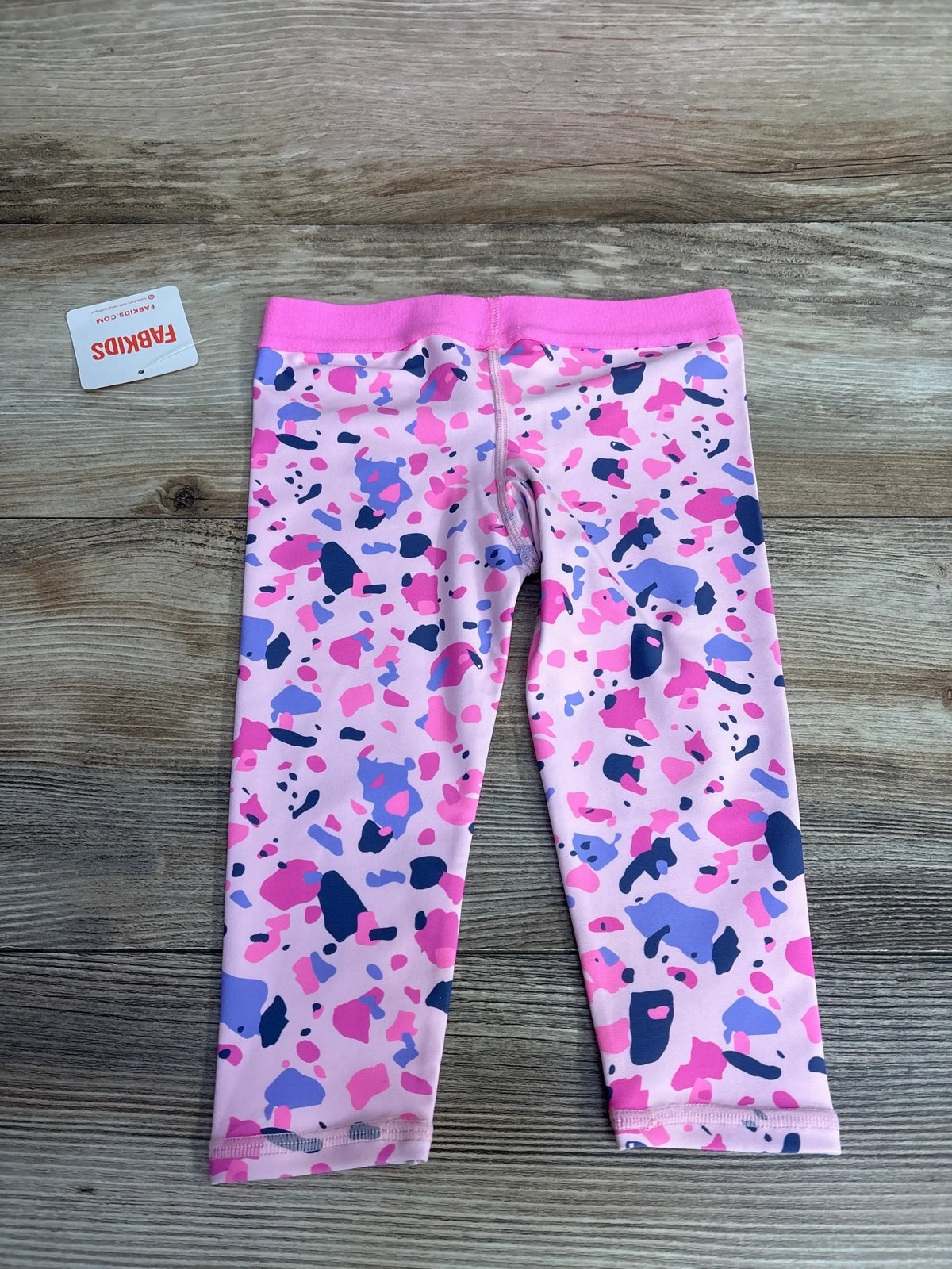 Pink and purple girls' leggings with abstract print on wood background