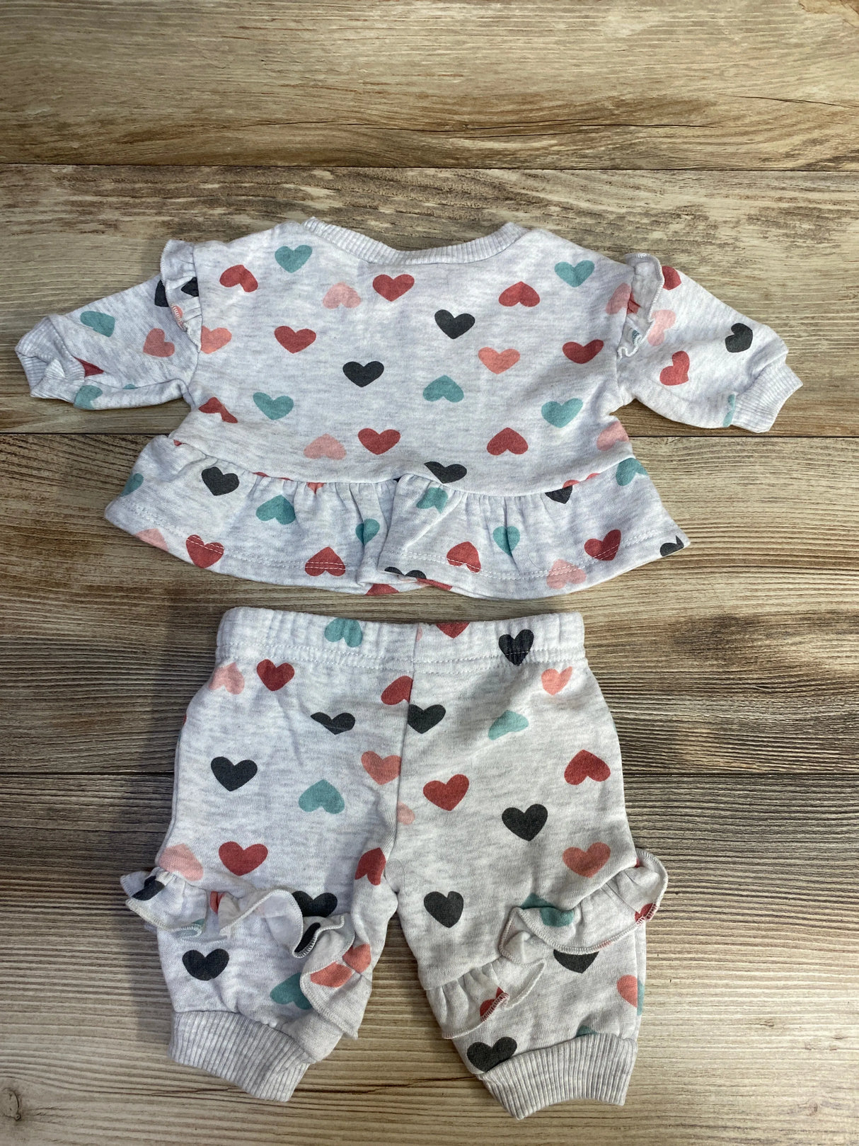 Baby girl heart print outfit set with ruffle sweatshirt and pants on wood background