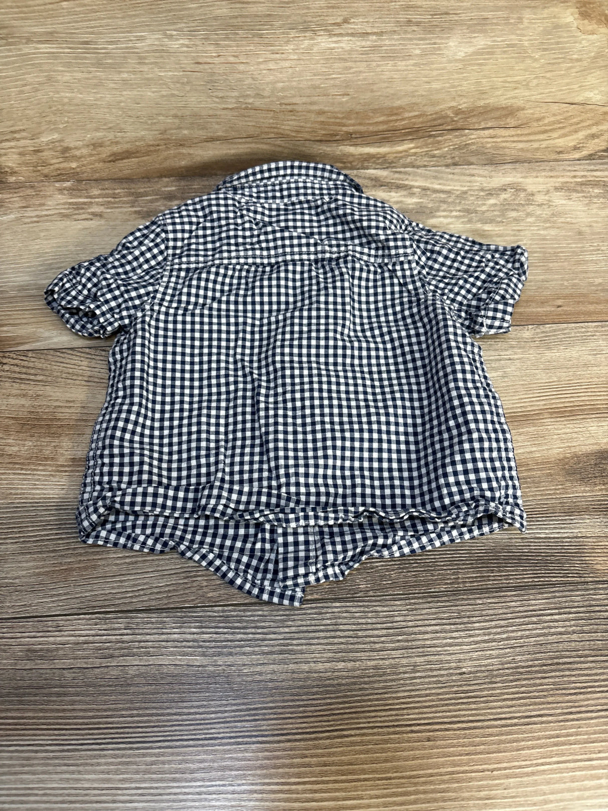 Back of a short sleeve black and white gingham toddler shirt on wood background