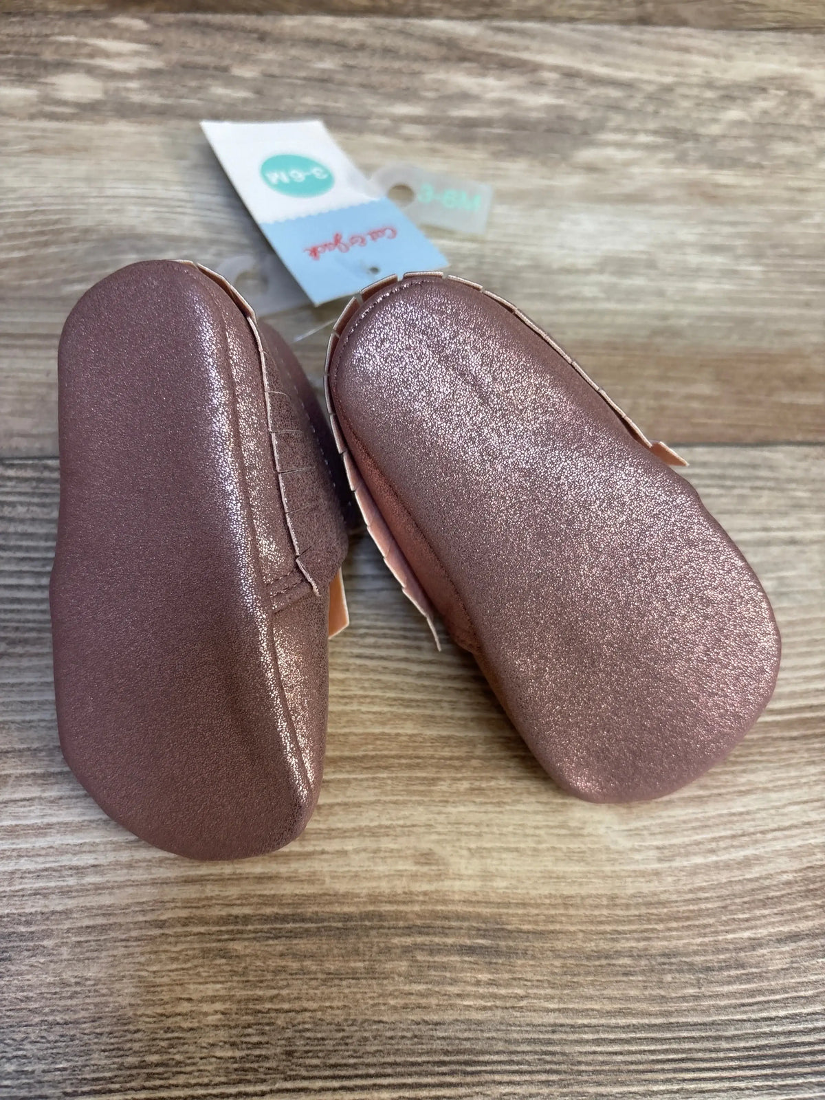 Rose gold baby shoes with soft soles on wood surface, infant size 3-6M, new with tags