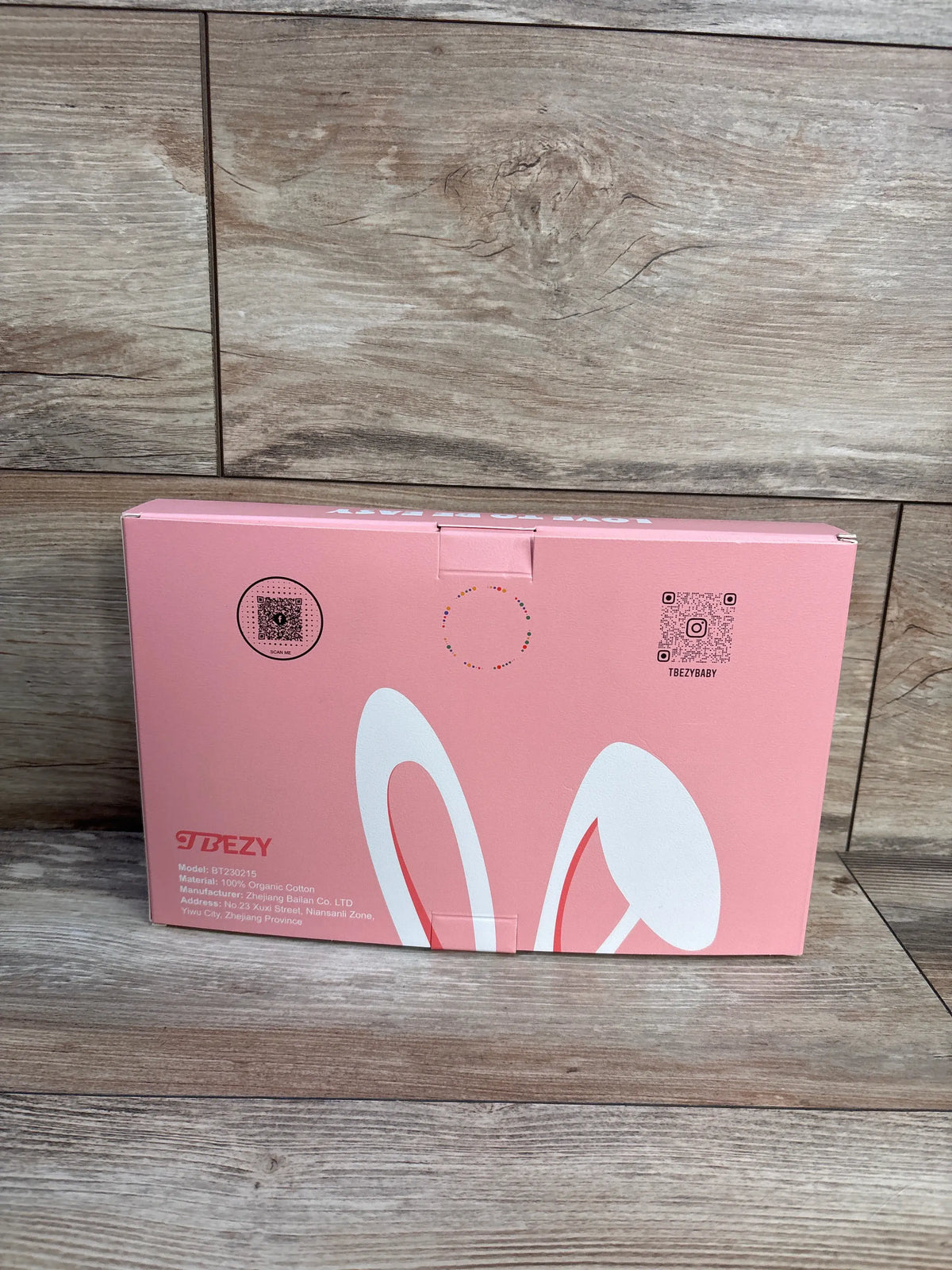 Front view of pink TBEZY hooded bunny towel packaging with white bunny-ear graphic on a wood-look floor