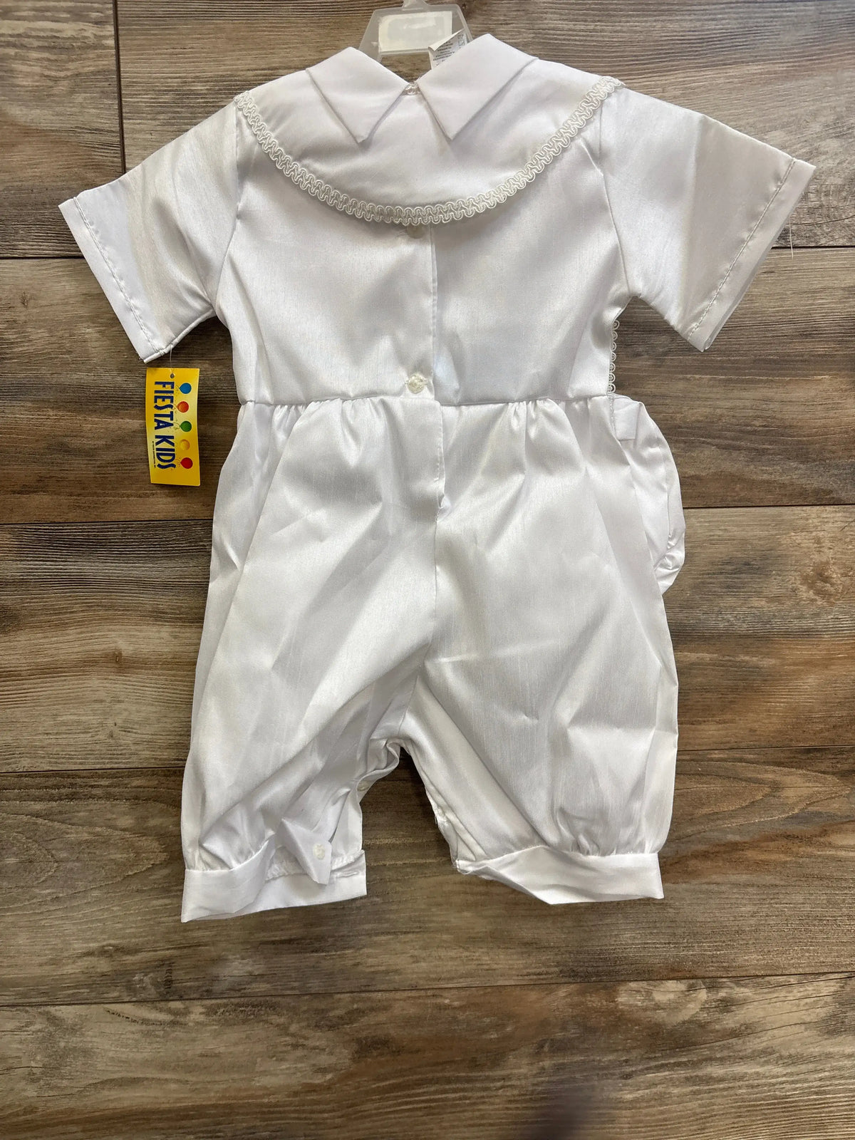 Front view of Fiesta Kids baptism and christening set showcasing white short sleeve formal outfit with decorative collar trim on a wood surface