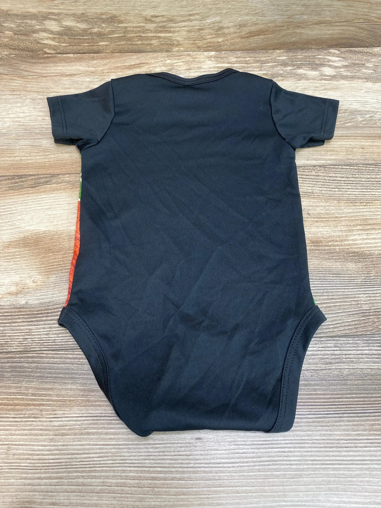 Back view of black Chicago Bears baby bodysuit showcasing short sleeves and snap crotch, laid flat on wood background
