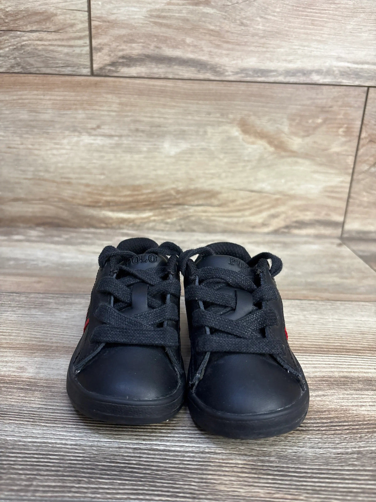 Front view of Polo Ralph Lauren Quilton Bear sneakers showcasing black lace-up styling and Polo embroidery on tongues with wood-look floor background