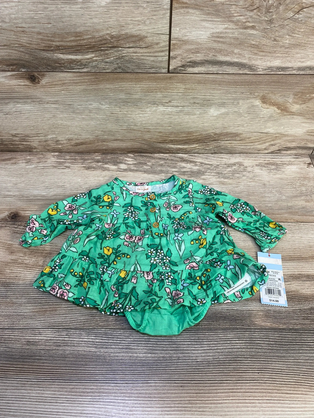 Flat lay of Cat and Jack green floral henley dress and bloomers showing ruffled tiers and buttons on light wood background
