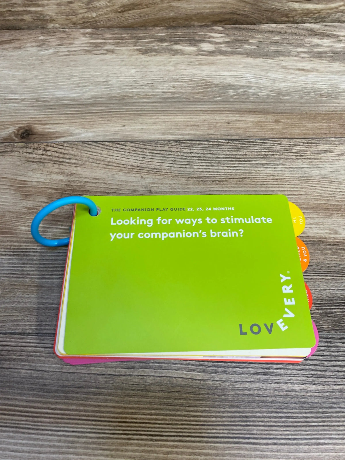 Lovevery play guide for toddlers on wooden table, green cover with white text and blue ring