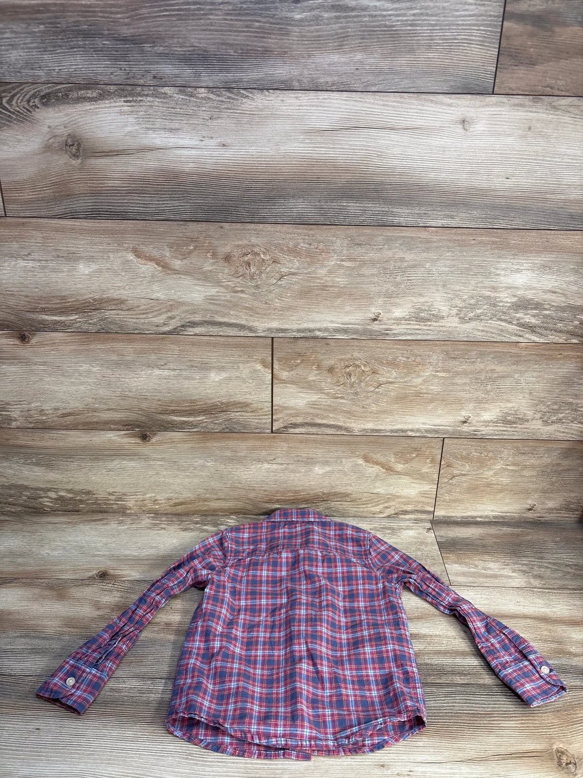 Back view of OshKosh red plaid button-up shirt, size 5T, showcasing long sleeves and collared design on a wood floor