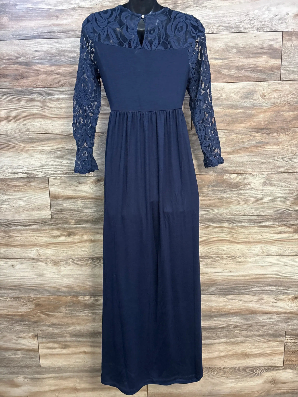Front view of navy maternity maxi dress with lace sleeves and yoke, empire waist, on mannequin against wood background
