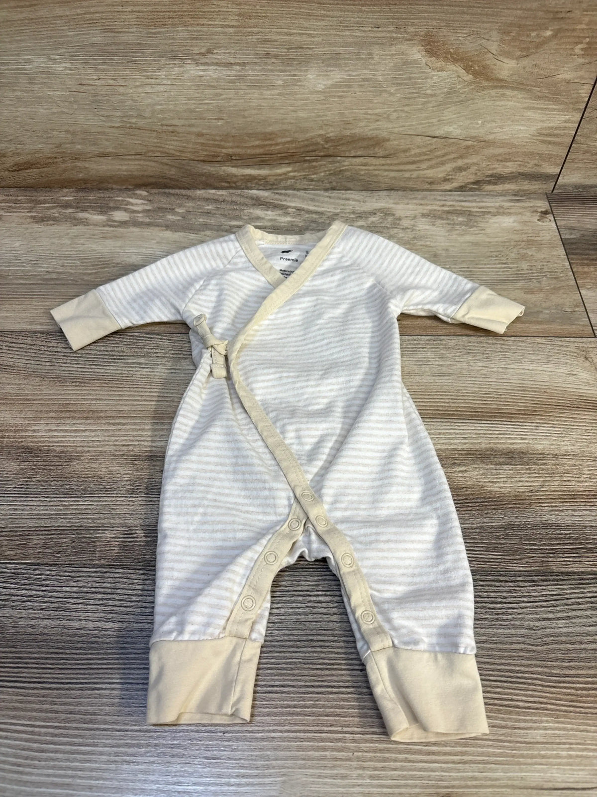 Flat lay of cream heather striped kimono tie one-piece preemie showing side-tie wrap closure and snap leg openings on wood floor