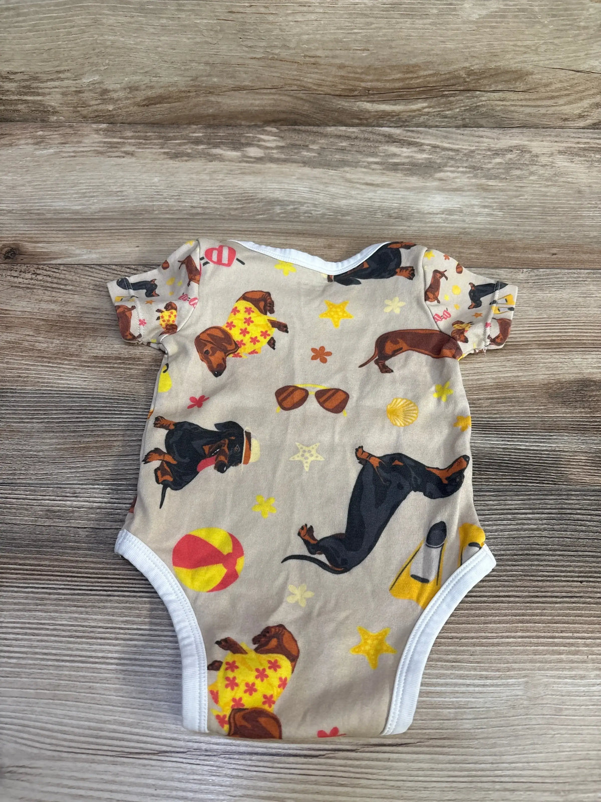 Front view of Vvfelixl bodysuit showcasing tan fabric with dachshund dog print and white trim on wood plank floor