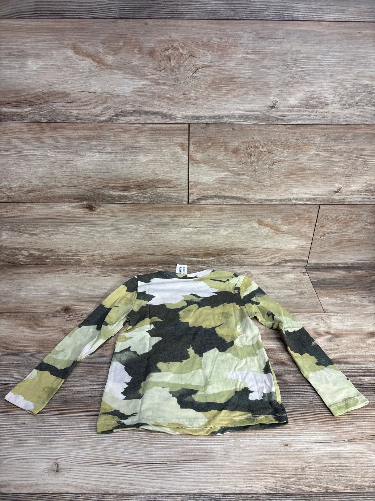 Kids' long sleeve camo shirt in green, yellow and white on wood background