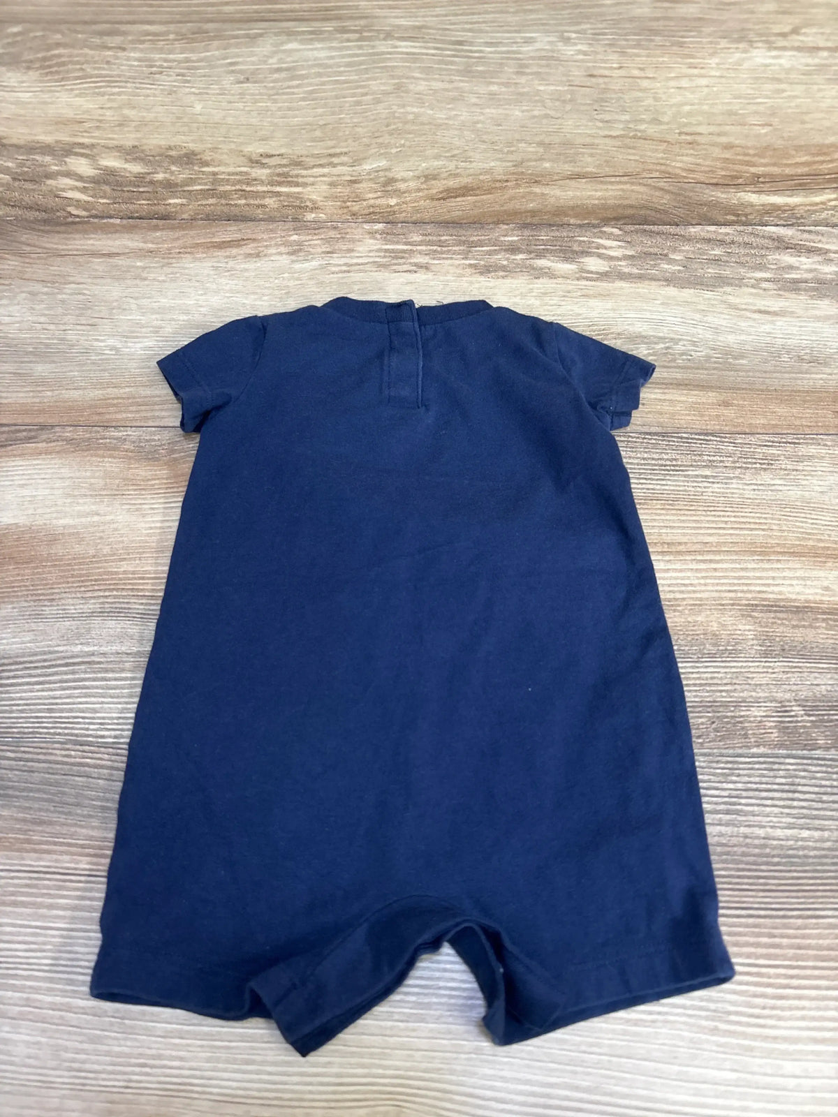 Flat lay of Nike navy shortie romper (6 months), back view showing short sleeves and crew neckline on wood background