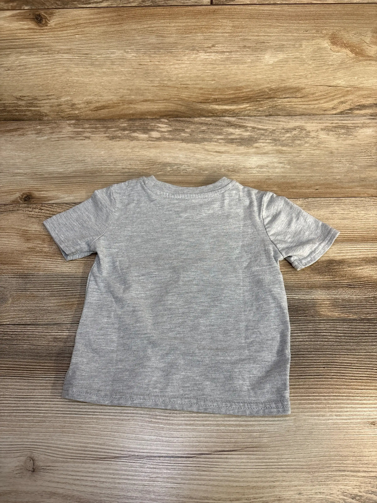 Plain gray short-sleeve toddler t-shirt laid flat on wooden surface
