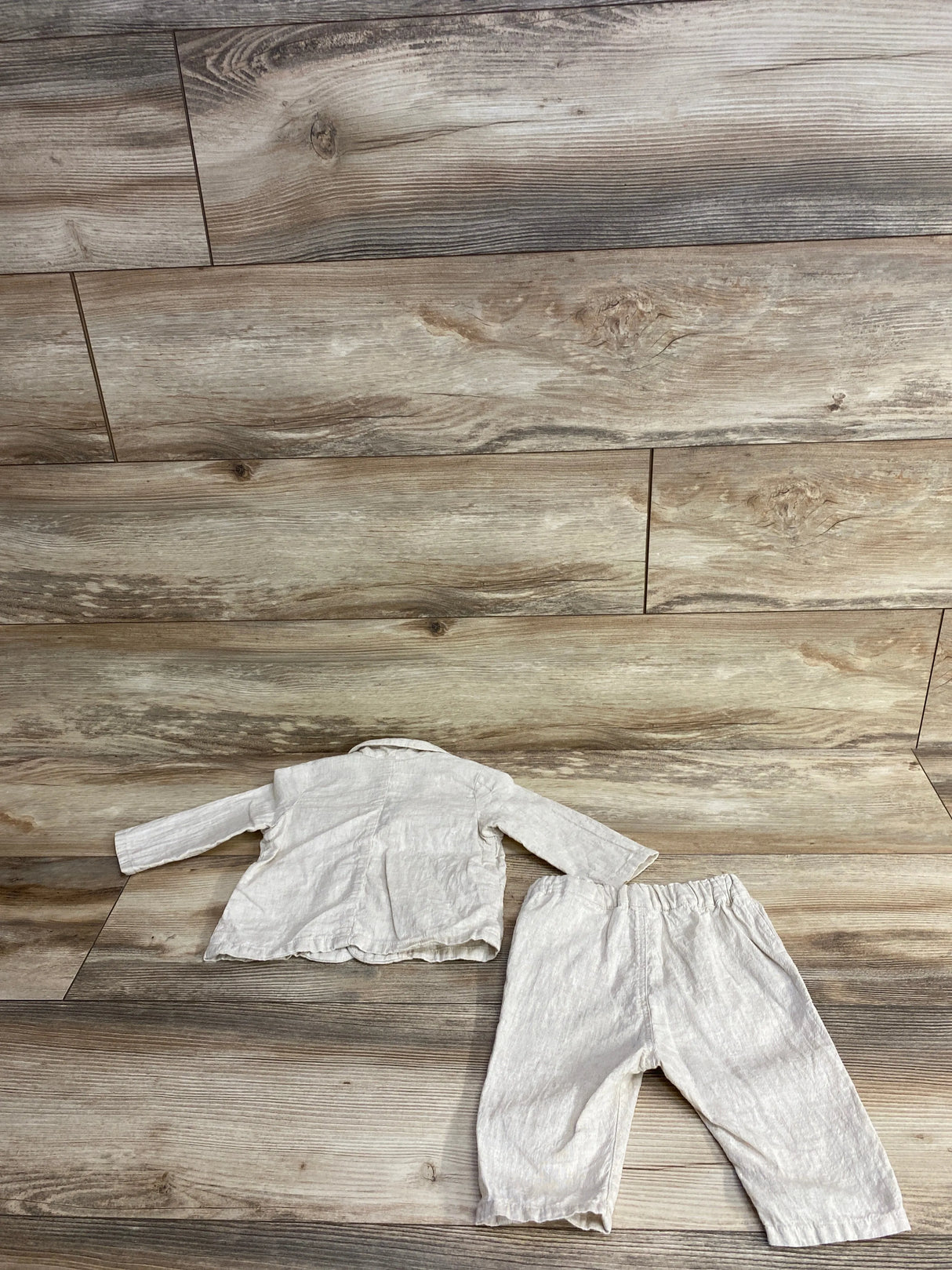 Light beige long sleeve toddler shirt and matching elastic waist pants on wood plank floor