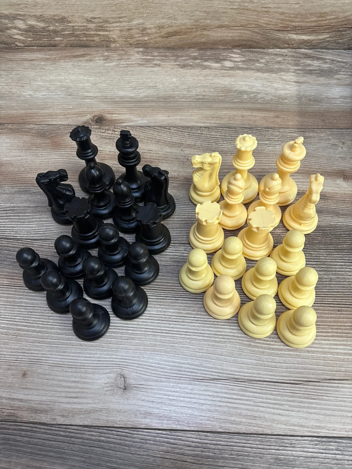 Top-down view of EasyGo giant chess set 3 by 4 ft showing black and ivory plastic pieces on wood background