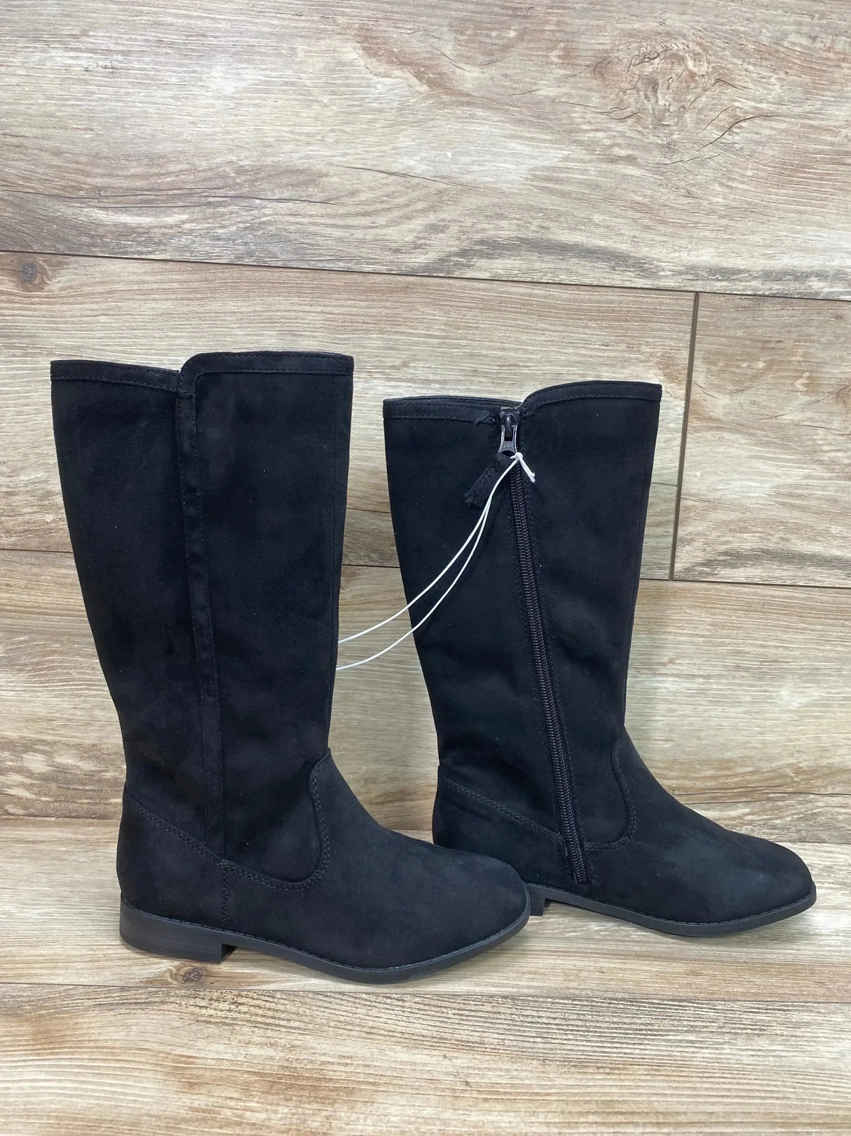 Side view of Cat and Jack Mylah toddler tall black riding boots showcasing inner zipper and low heel with wood floor background