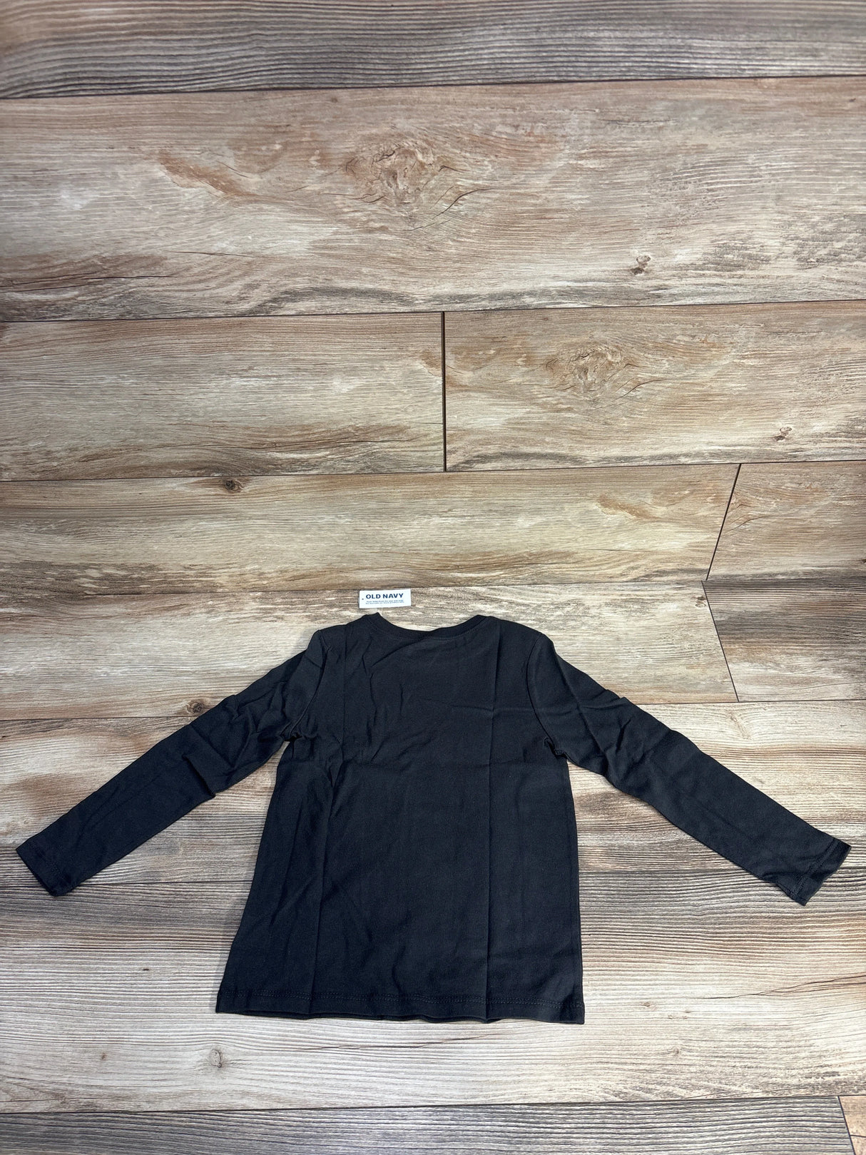 Old Navy black long sleeve kids shirt on wood floor background