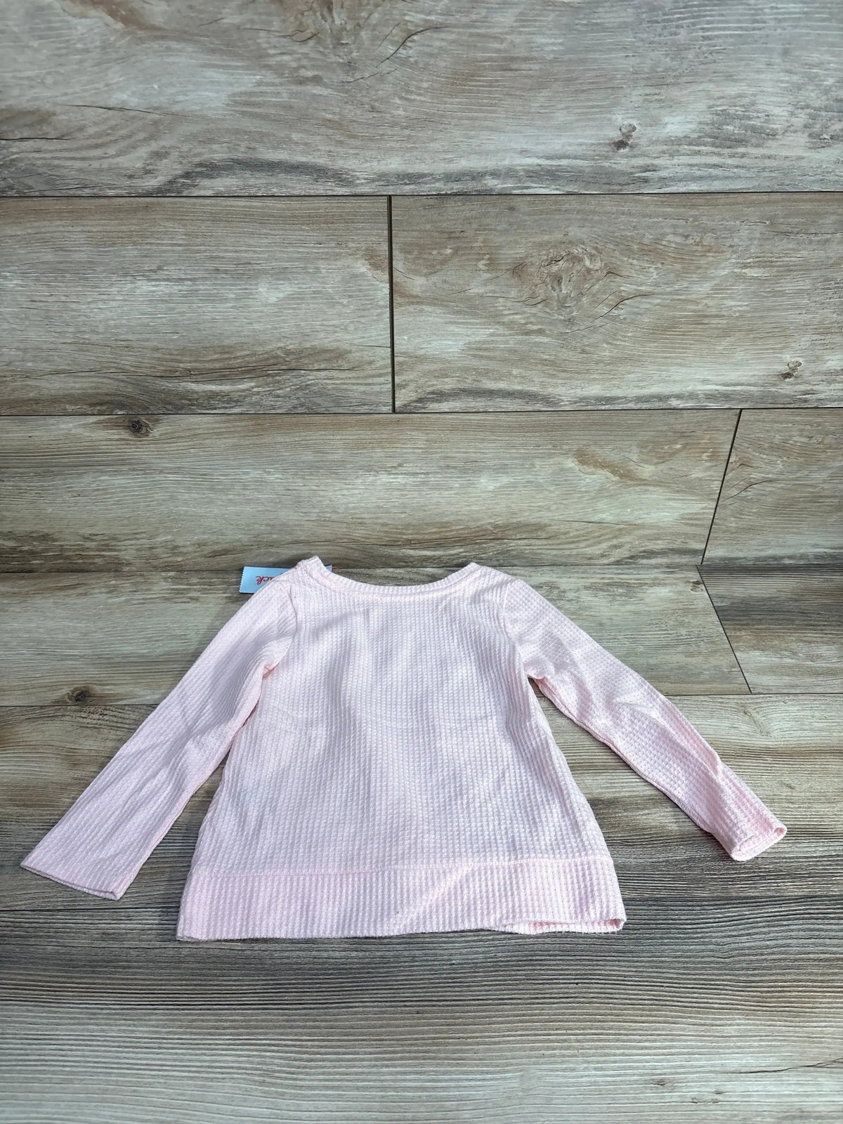 Light pink long sleeve waffle knit toddler shirt on wooden background
