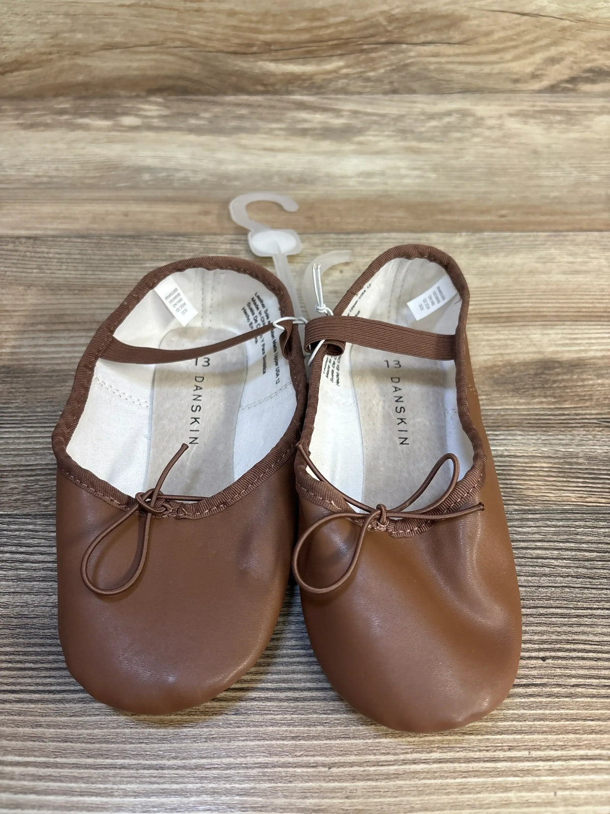Toddler brown ballet flats with elastic strap and bow on wooden background