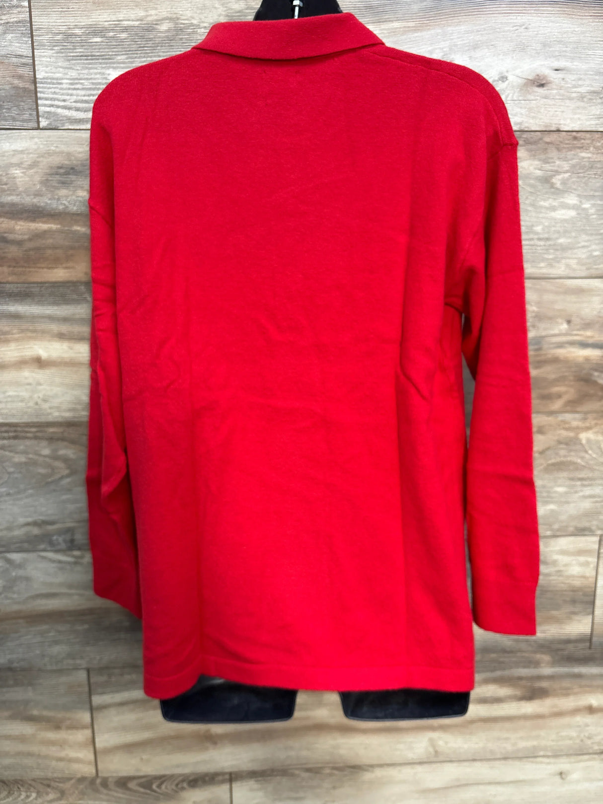 Back view of a red long sleeve collared shirt on hanger, wood background