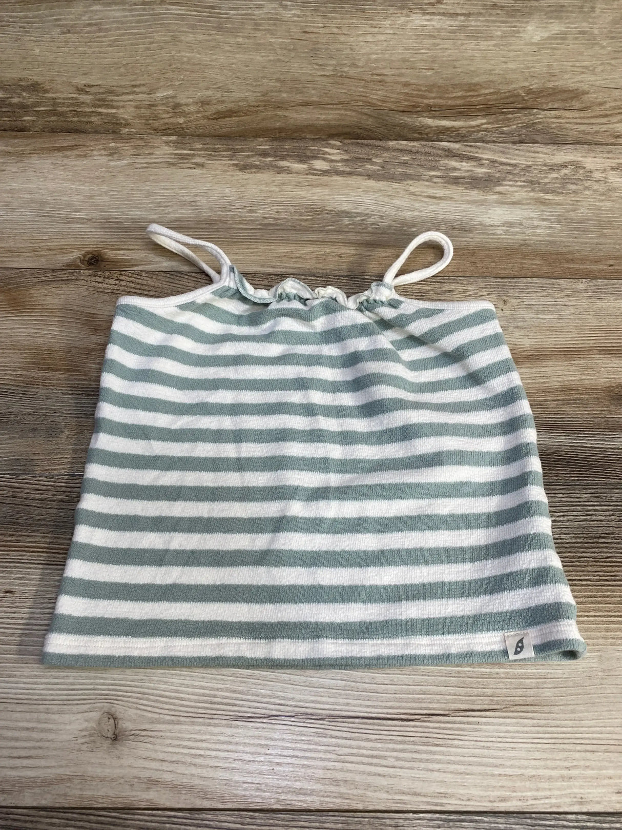 Flat lay of green and white striped toddler tube top with thin straps and gathered elastic neckline on wood background
