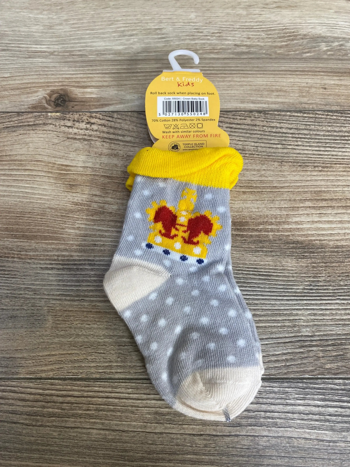 Top-down view of baby sock size 9-24 months showcasing red and yellow crown motif, yellow cuff and white polka dots on wood background
