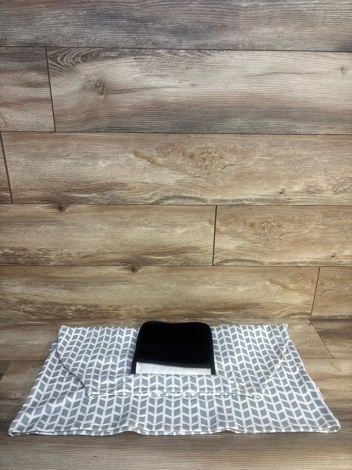 Flat view of KeaBabies Warmzy Car Seat Cover in gray Kite pattern showcasing its black headrest section on a wood floor