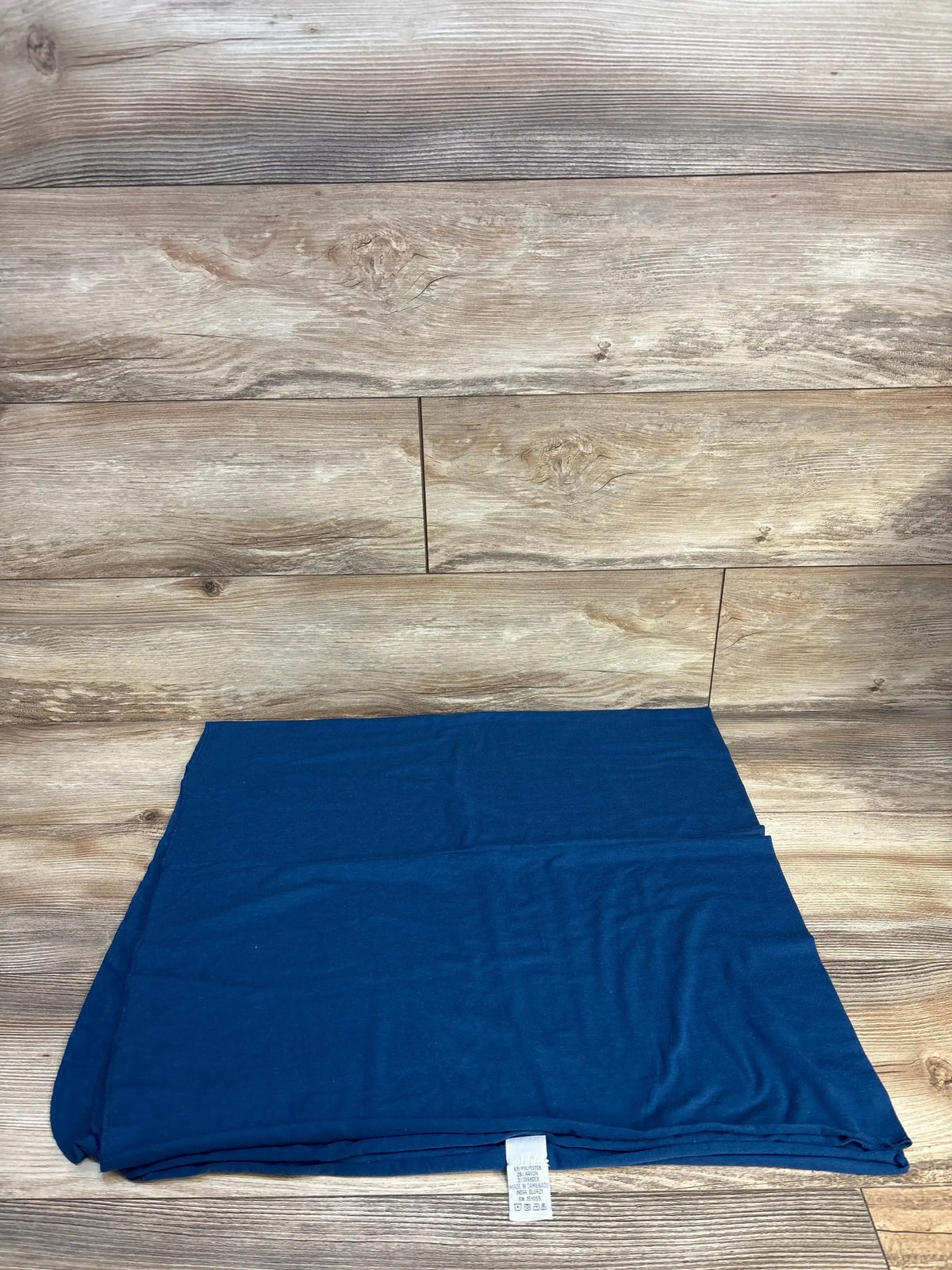 Folded front view of Copper Pearl Robin knit swaddle blanket showcasing navy blue knit fabric with wooden plank background