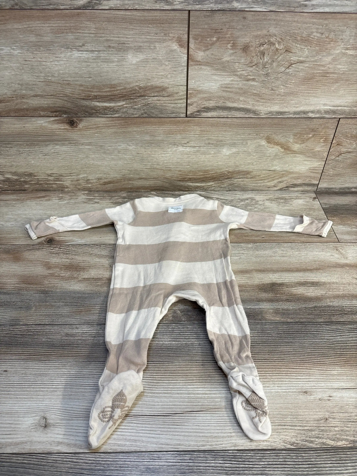 Striped baby footed onesie with soft grip soles on wooden floor
