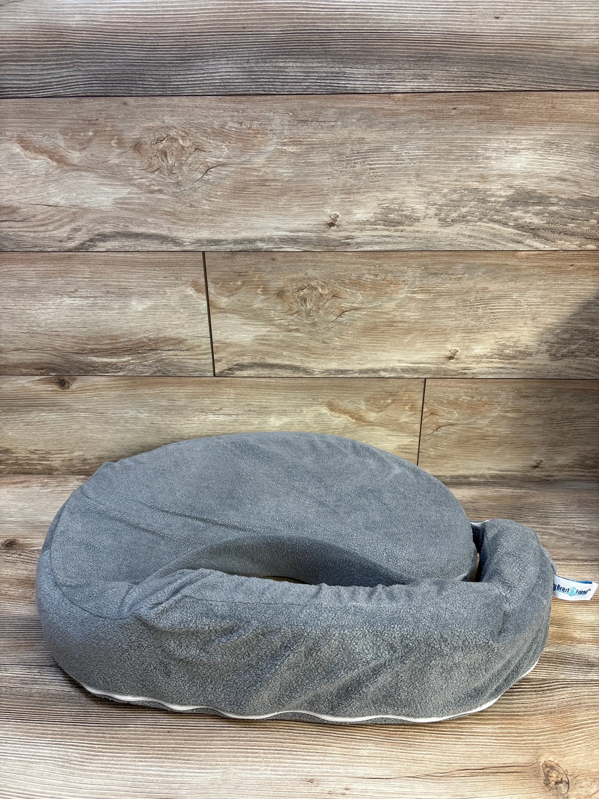 Gray nursing pillow with soft cover on wooden floor, baby gear accessory