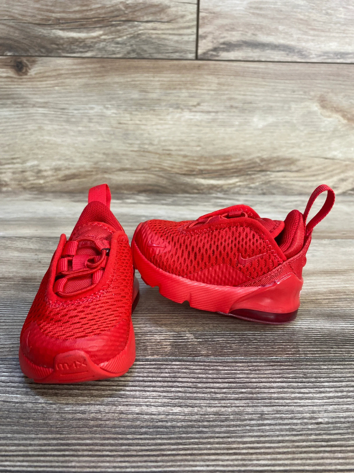 Red mesh toddler athletic sneakers with rubber soles on wood floor background