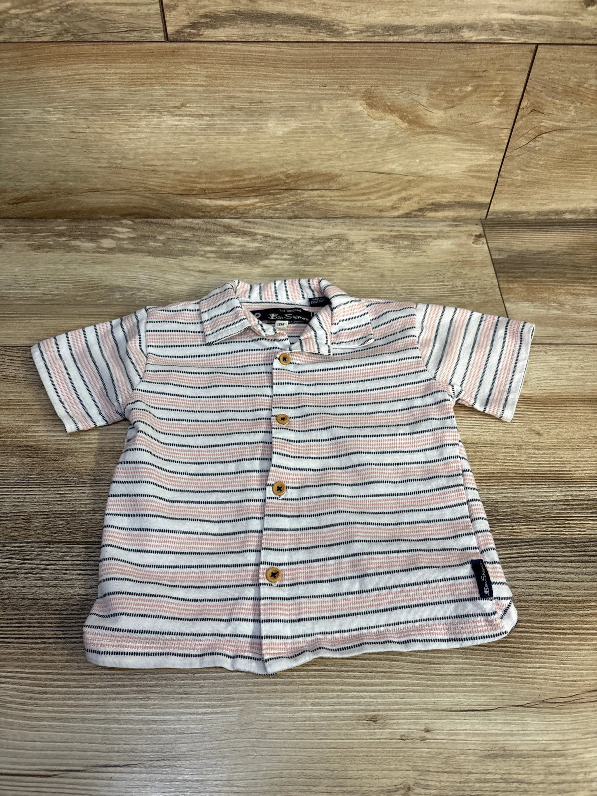 Front view of Ben Sherman white striped button-up shirt showcasing short sleeves and button closure on a wood-grain background