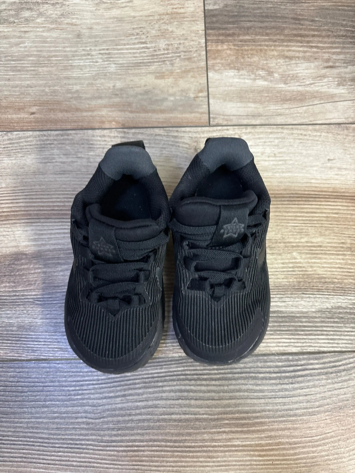 Top view of Nike Star Runner 4 TD sneakers showcasing ribbed upper and hook-and-loop strap on wood-look floor, size 6C