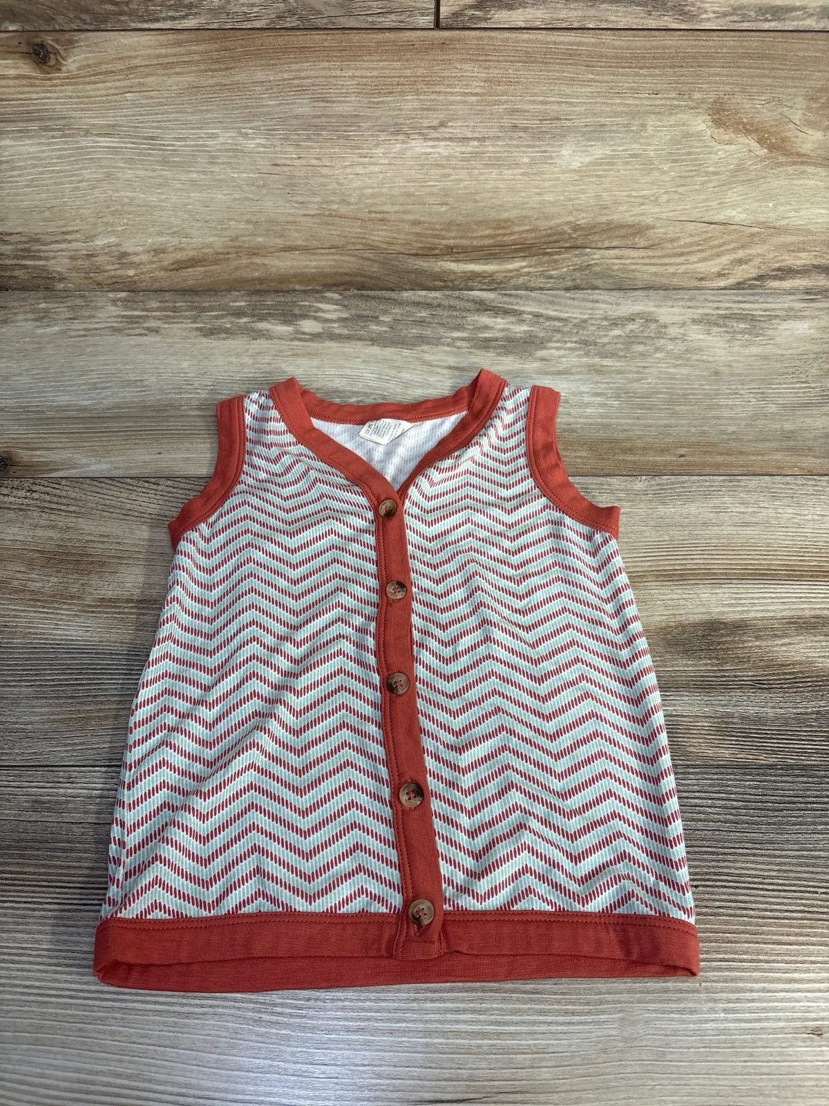 Front view of Kate Quinn orange bamboo button-up tank top showcasing chevron pattern and five-button front on a wood background