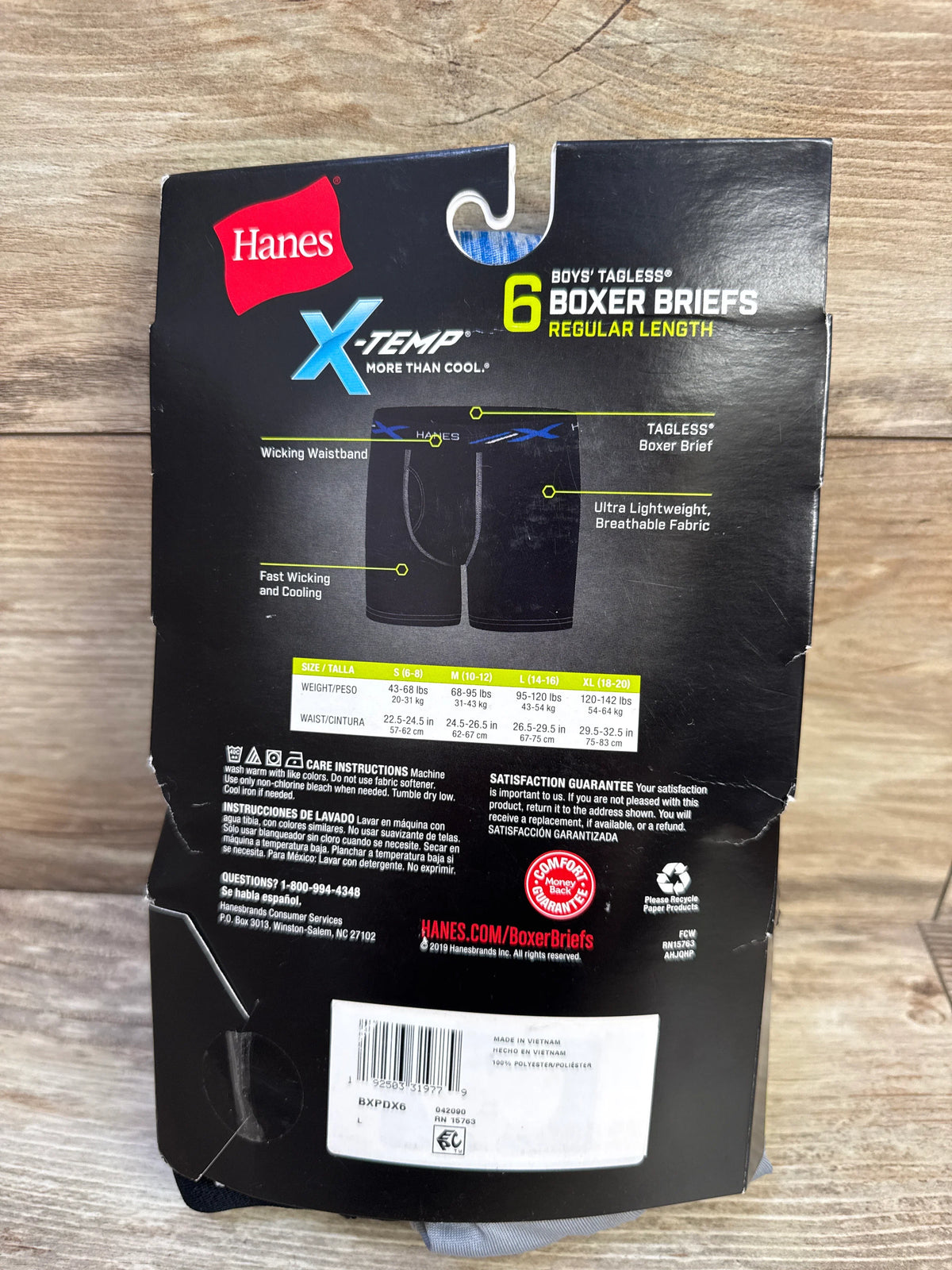 Back of Hanes X-Temp boys’ 6-pack boxer briefs packaging showing tagless, wicking waistband and size chart on wood
